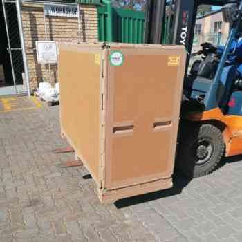 Industrial packaging crate being transported by forklift, made from durable honeycomb boards.