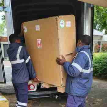 Two workers loading a custom honeycomb crate into a delivery vehicle