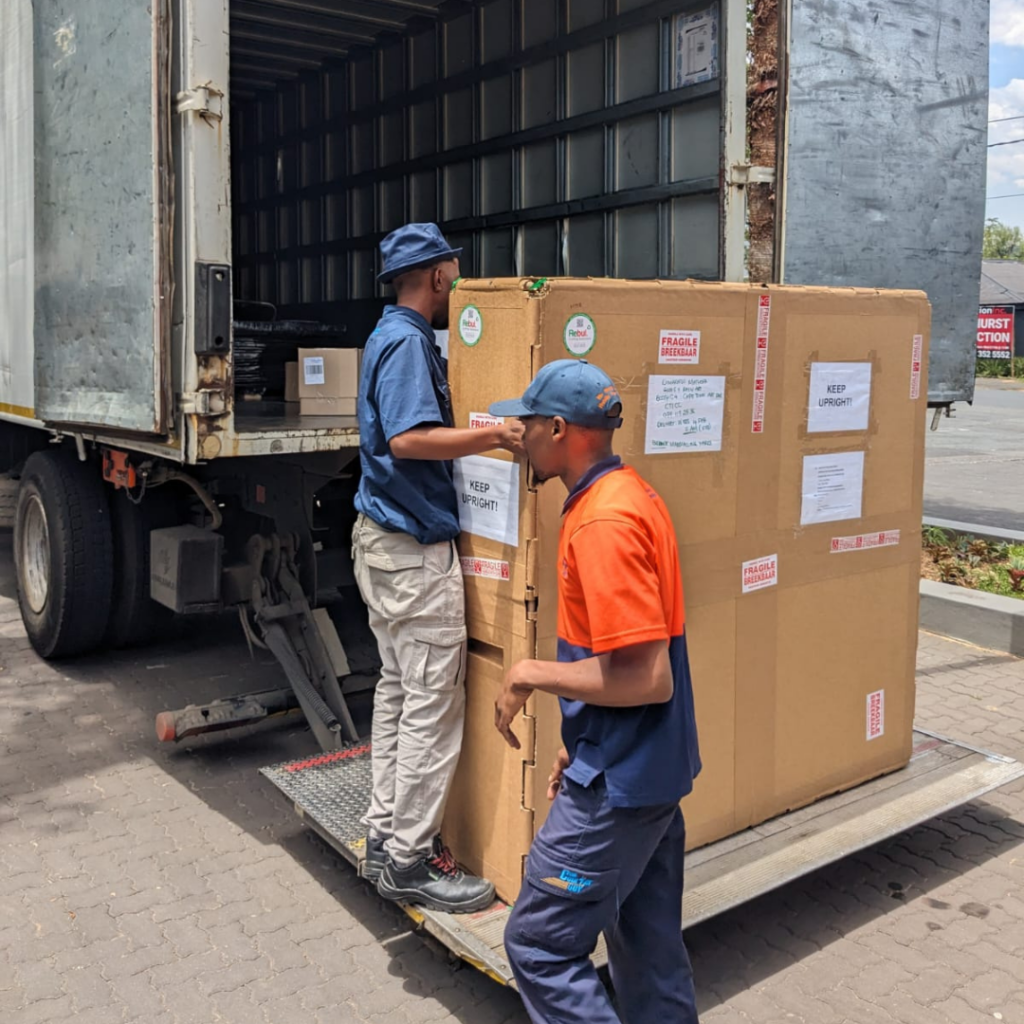 Workers loading a custom-packaged industrial product onto a delivery truck for transport