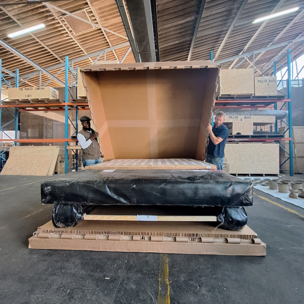 Large manufactured industrial component positioned for custom protective packaging in a factory