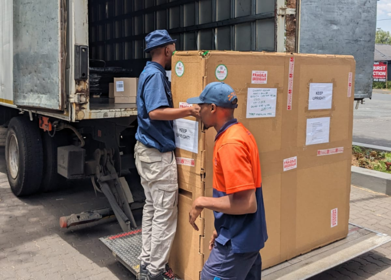 Workers loading a custom-packaged industrial product onto a delivery truck for transport