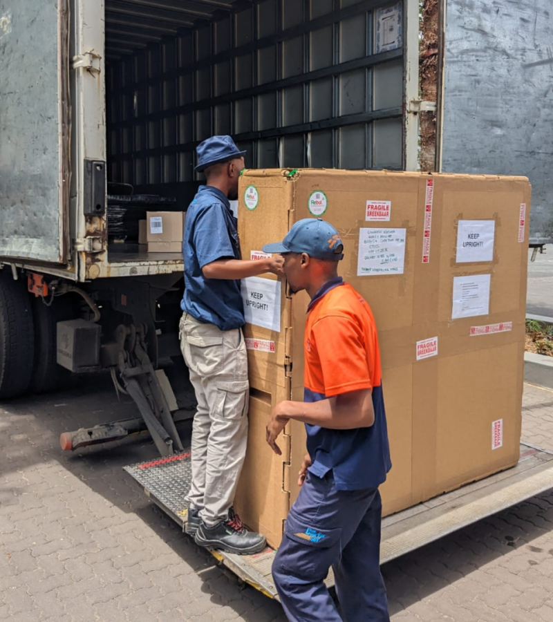Workers loading a custom-packaged industrial product onto a delivery truck for transport
