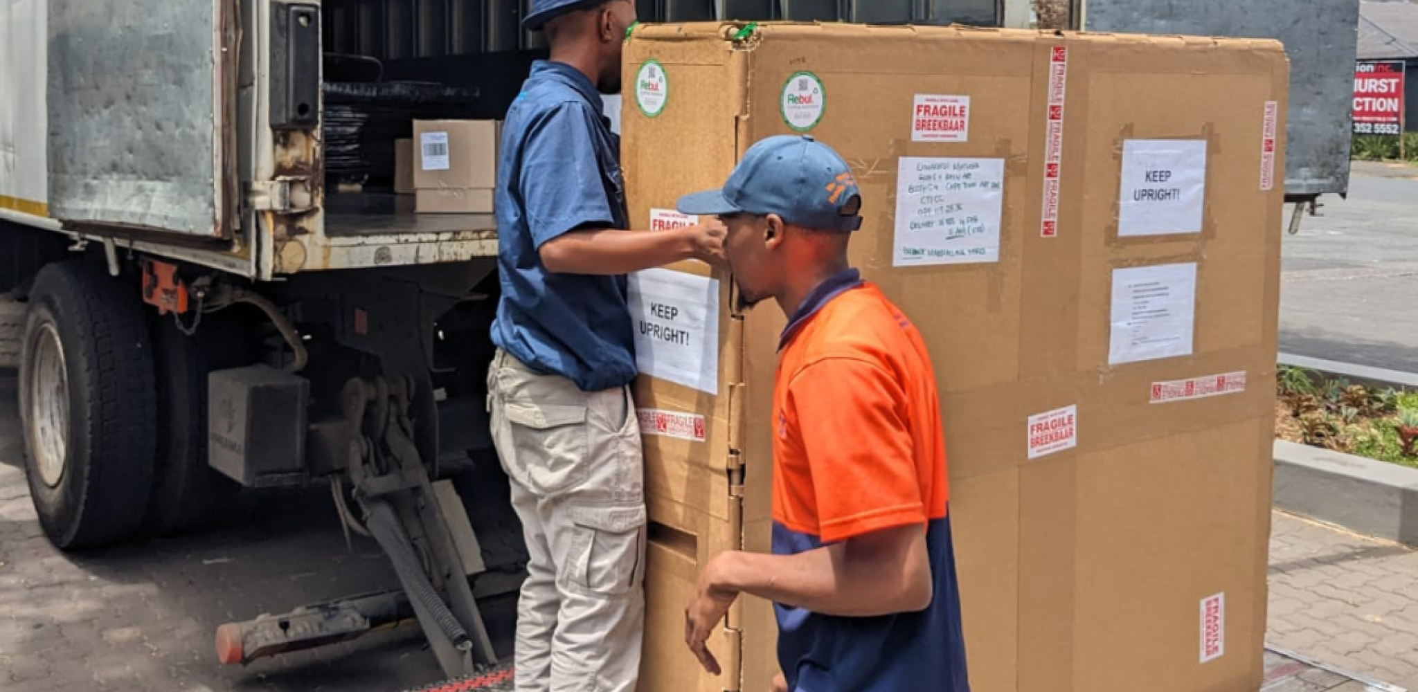 Workers loading a custom-packaged industrial product onto a delivery truck for transport