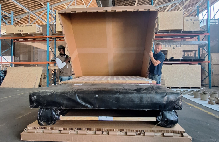 Large manufactured industrial component positioned for custom protective packaging in a factory