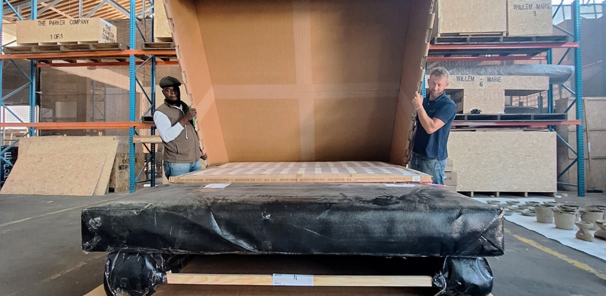 Large manufactured industrial component positioned for custom protective packaging in a factory